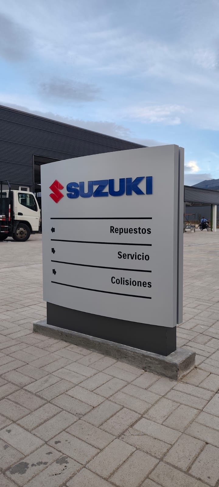 Tótem publicitario Suzuki con señalética exterior direccional